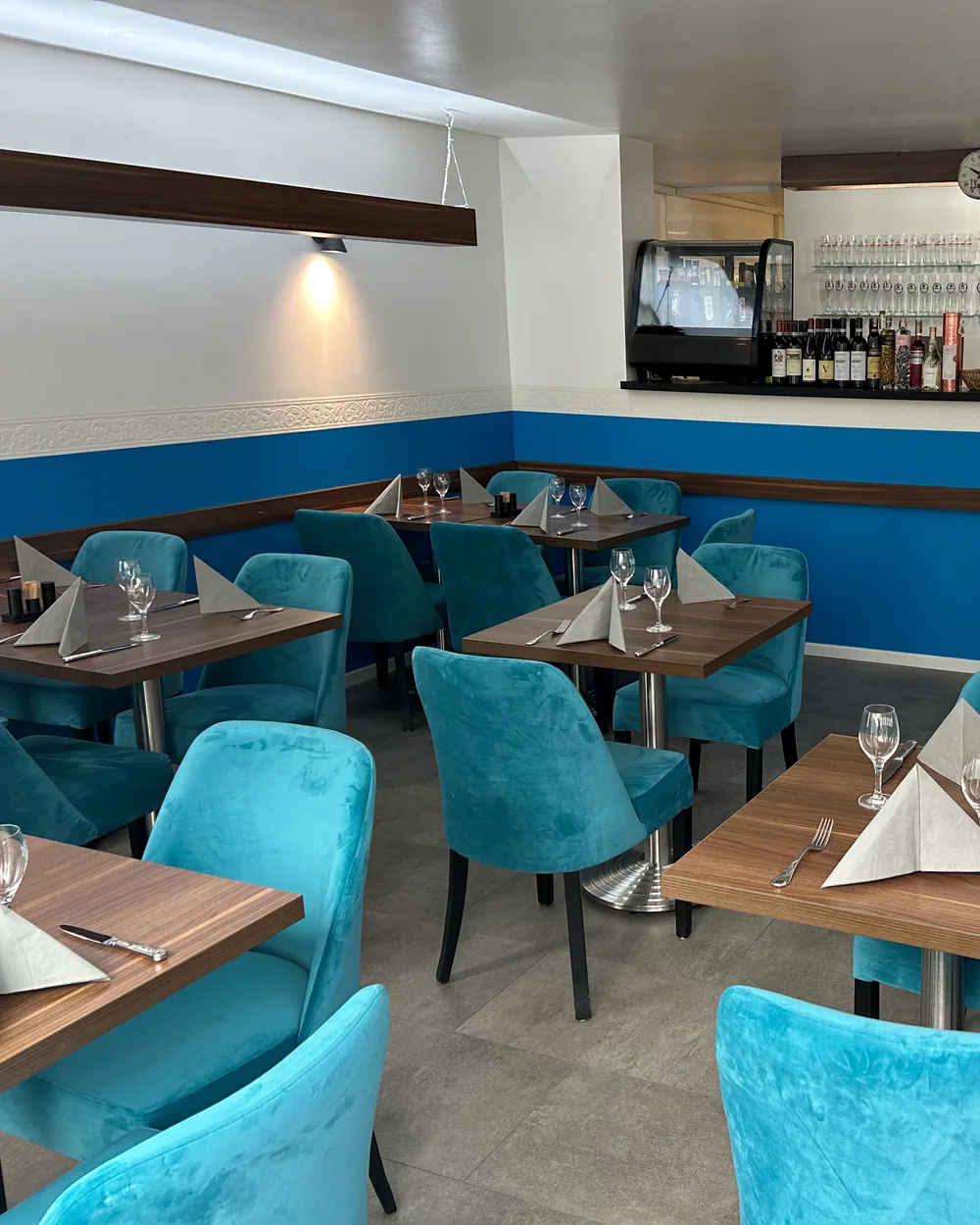 La Pasteria dining room with set tables, blue chairs and bar