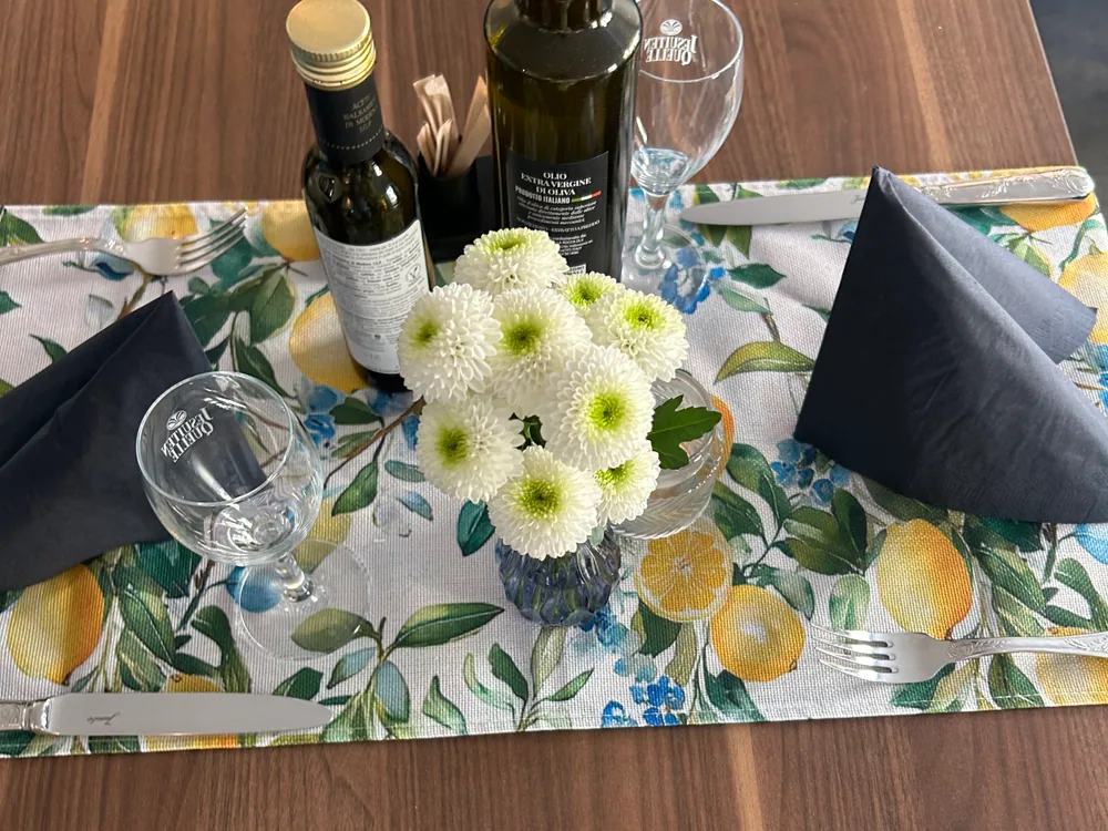 Tavolo apparecchiato con fiori, bicchieri e olio d'oliva